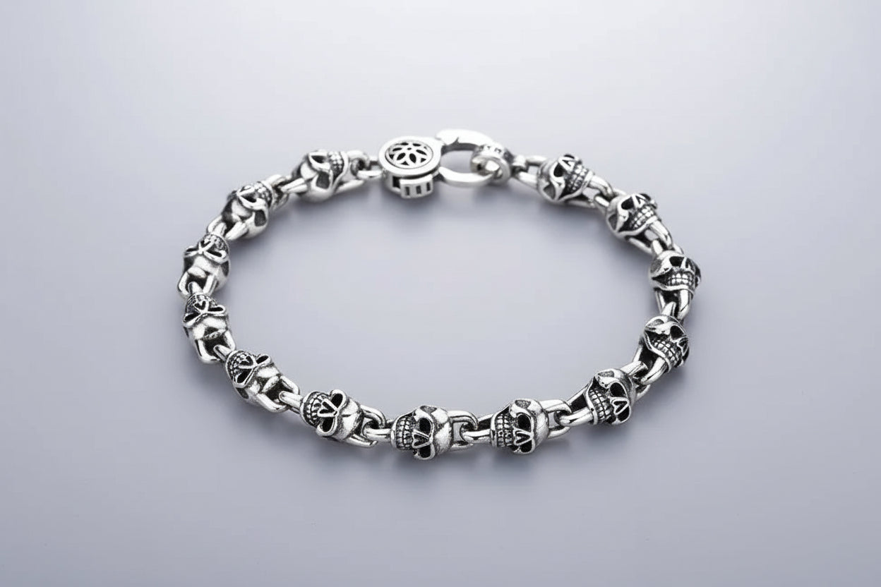 Silver bracelet with skull designs on a dark background